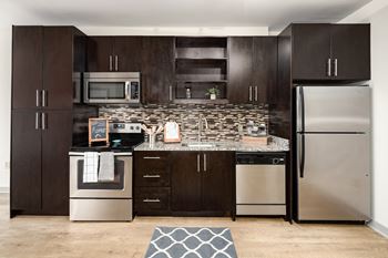 A kitchen with dark brown cabinets and stainless steel appliances.